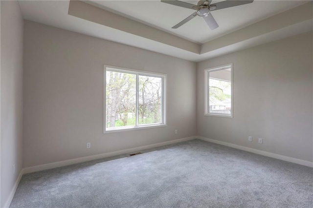 spare room featuring baseboards, a raised ceiling, a ceiling fan, and carpet flooring