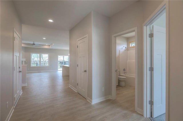 hallway featuring recessed lighting, light wood finished floors, and baseboards