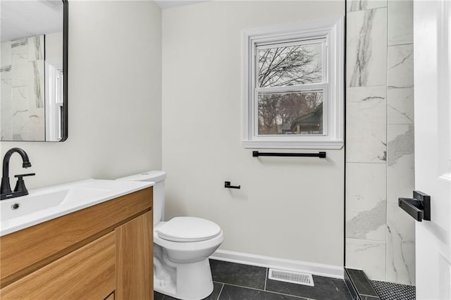 bathroom featuring vanity, a tile shower, tile patterned floors, and toilet