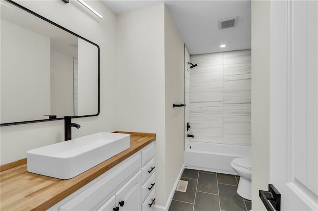 full bathroom featuring tiled shower / bath, vanity, toilet, and tile patterned flooring