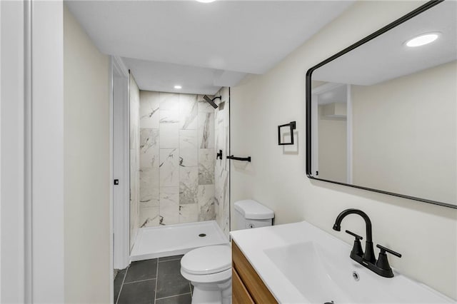 bathroom with vanity, tile patterned flooring, toilet, and tiled shower