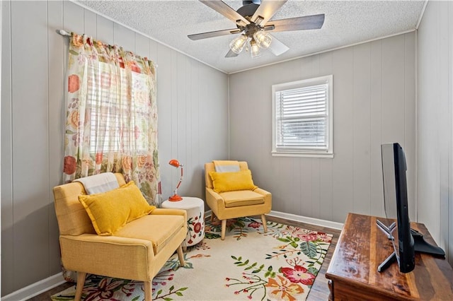 sitting room featuring ceiling fan, baseboards, a textured ceiling, and wood finished floors