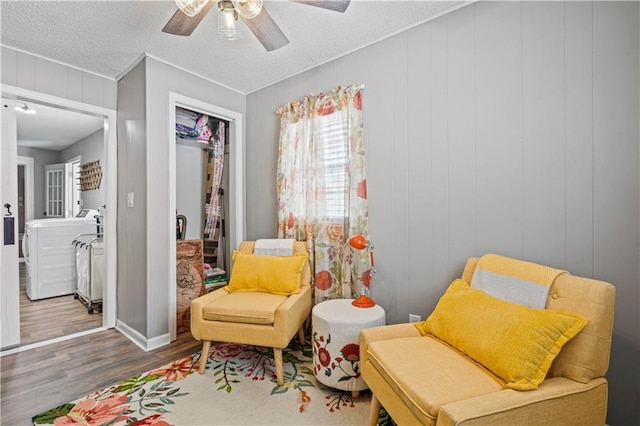 living area featuring washer / clothes dryer, ceiling fan, a textured ceiling, and wood finished floors