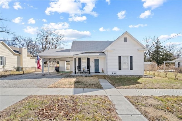 view of front of house featuring a porch, a front yard, central AC, fence, and driveway