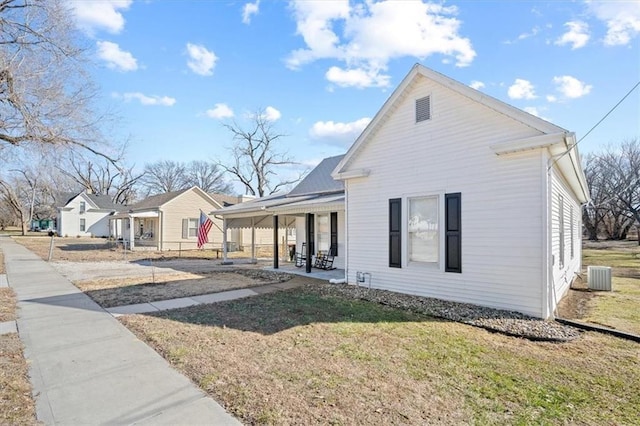 view of front of property with a front yard, covered porch, and central AC unit