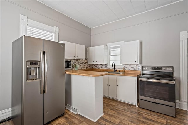 kitchen with white cabinetry, appliances with stainless steel finishes, dark wood finished floors, and a sink