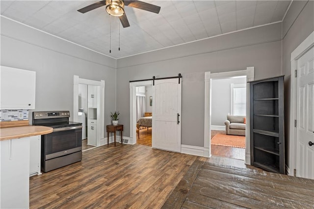 kitchen featuring a barn door, dark wood finished floors, ceiling fan, stainless steel range with electric cooktop, and white cabinetry