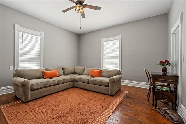 living area featuring dark wood-type flooring, baseboards, and a ceiling fan