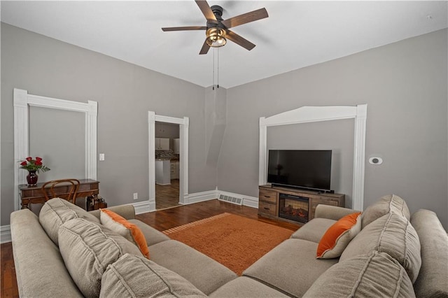 living room featuring a ceiling fan, wood finished floors, visible vents, and baseboards