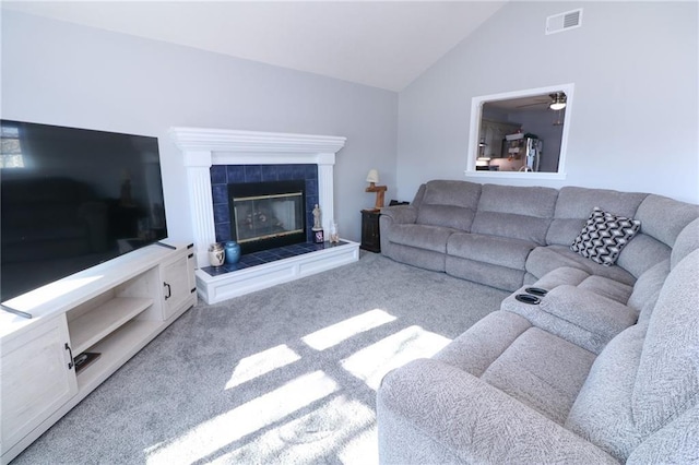 carpeted living room with a tile fireplace and lofted ceiling