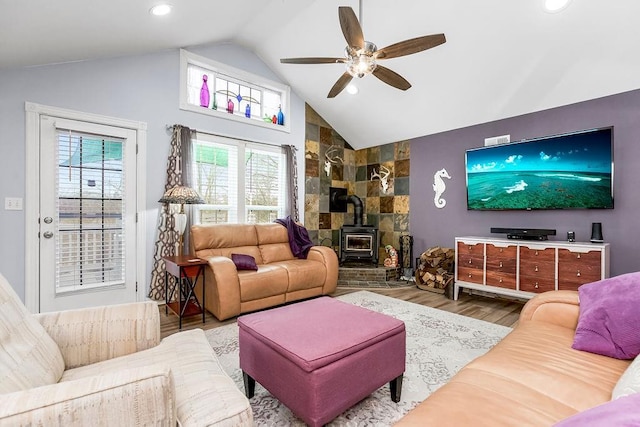 living room with vaulted ceiling, a wood stove, hardwood / wood-style floors, and ceiling fan