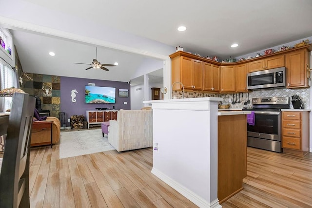 kitchen with vaulted ceiling, light hardwood / wood-style floors, kitchen peninsula, and appliances with stainless steel finishes