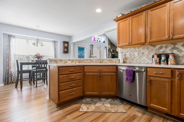 kitchen with pendant lighting, decorative backsplash, light hardwood / wood-style flooring, and stainless steel dishwasher