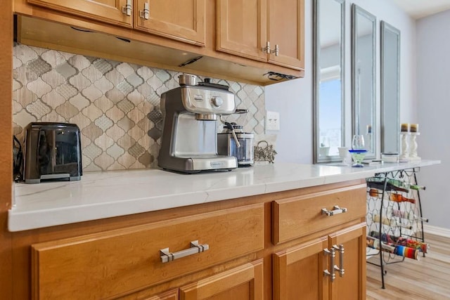 kitchen with tasteful backsplash, light stone counters, and light hardwood / wood-style floors