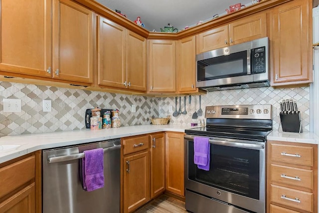 kitchen featuring light stone countertops, appliances with stainless steel finishes, backsplash, and light wood-type flooring