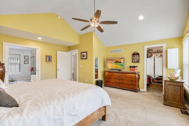 bedroom with ceiling fan, high vaulted ceiling, ensuite bathroom, a walk in closet, and light colored carpet