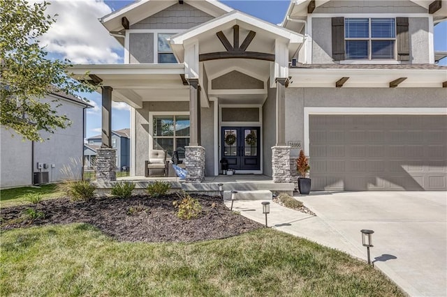 property entrance featuring covered porch, a garage, a yard, central air condition unit, and french doors