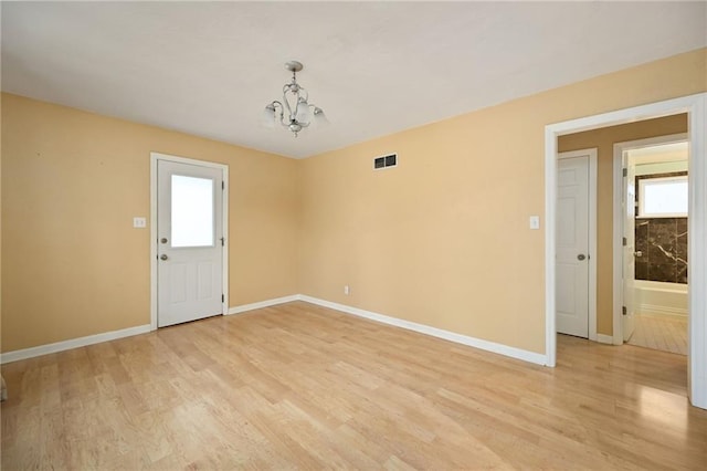 unfurnished room featuring an inviting chandelier and light hardwood / wood-style floors