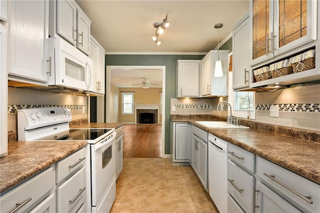 kitchen with sink, white appliances, decorative light fixtures, and white cabinets