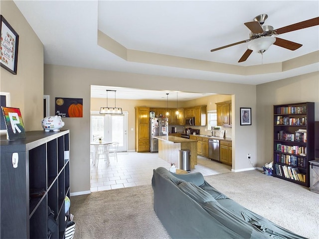 living room featuring plenty of natural light, a tray ceiling, and light carpet