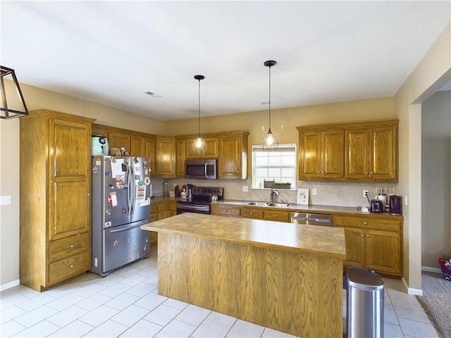 kitchen with pendant lighting, sink, stainless steel appliances, and a kitchen island