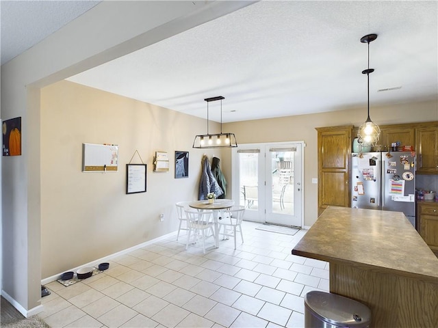 kitchen with light tile patterned floors, decorative light fixtures, and stainless steel refrigerator