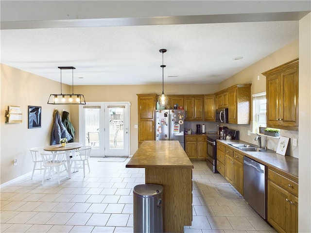 kitchen featuring appliances with stainless steel finishes, wood counters, sink, hanging light fixtures, and a center island