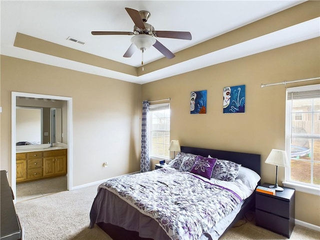 bedroom featuring a raised ceiling, light colored carpet, and multiple windows