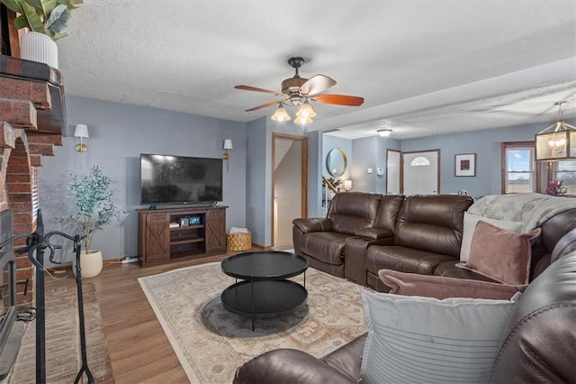 living room with hardwood / wood-style flooring, ceiling fan, a fireplace, and a textured ceiling