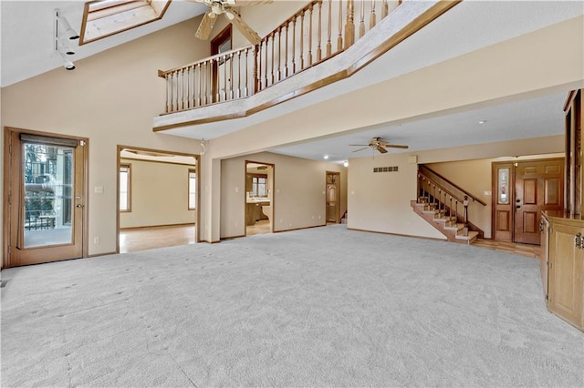 unfurnished living room with ceiling fan, high vaulted ceiling, and light carpet