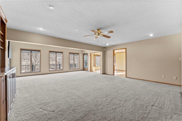 unfurnished living room with ceiling fan, light colored carpet, and a textured ceiling