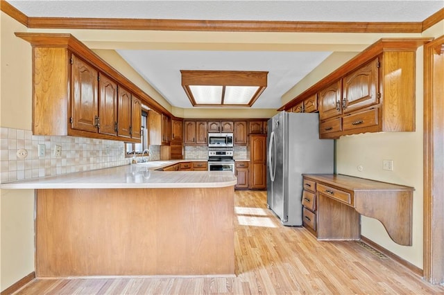 kitchen featuring appliances with stainless steel finishes, kitchen peninsula, light hardwood / wood-style flooring, and backsplash