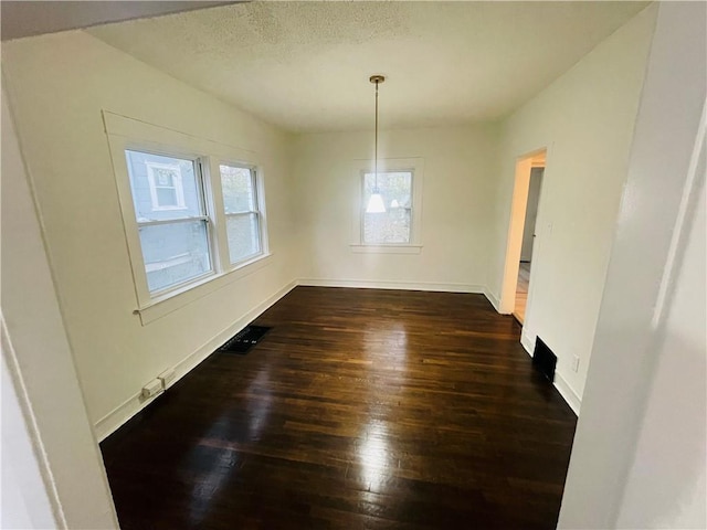 unfurnished dining area featuring dark wood-type flooring and a textured ceiling