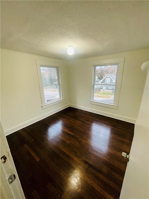 spare room featuring dark wood-type flooring and a textured ceiling