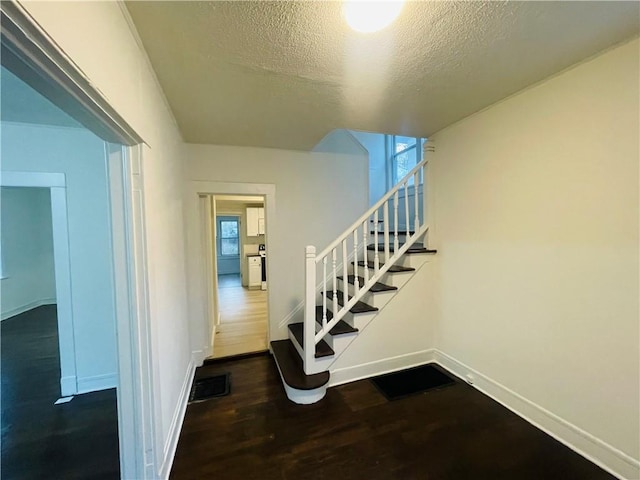 staircase with hardwood / wood-style floors and a textured ceiling