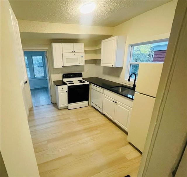 kitchen with sink, light wood-type flooring, white cabinets, white appliances, and a textured ceiling