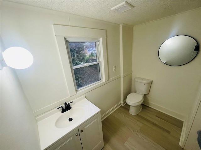 bathroom featuring vanity, hardwood / wood-style floors, a textured ceiling, and toilet