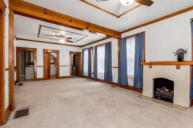 unfurnished living room with a fireplace, ornamental molding, ceiling fan, light carpet, and beam ceiling