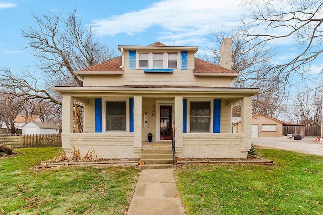 view of front of property with a porch, an outbuilding, a garage, and a front yard