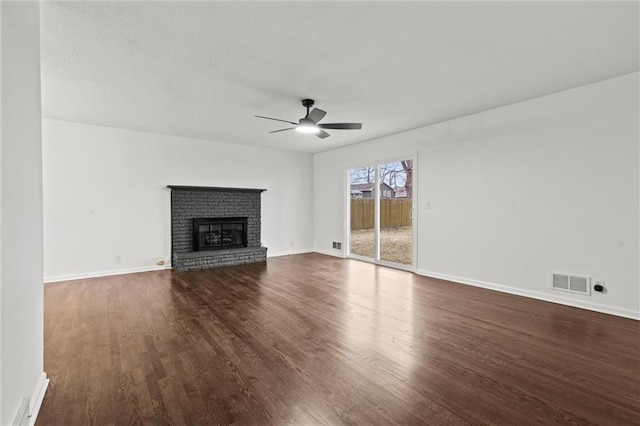 unfurnished living room with dark hardwood / wood-style flooring, a brick fireplace, and ceiling fan