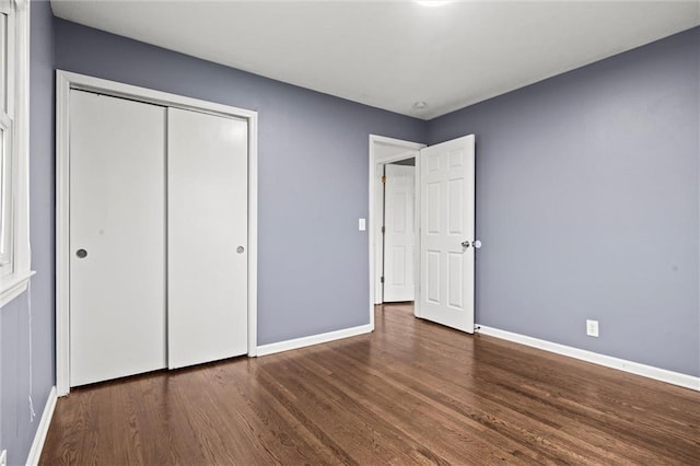 unfurnished bedroom with dark wood-type flooring and a closet