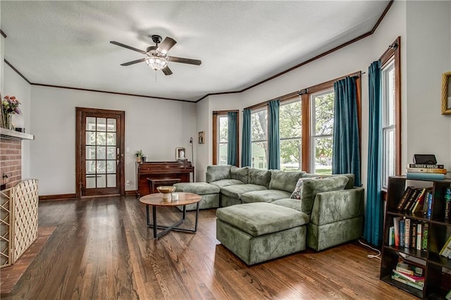 living room featuring a brick fireplace, crown molding, dark wood-type flooring, and ceiling fan