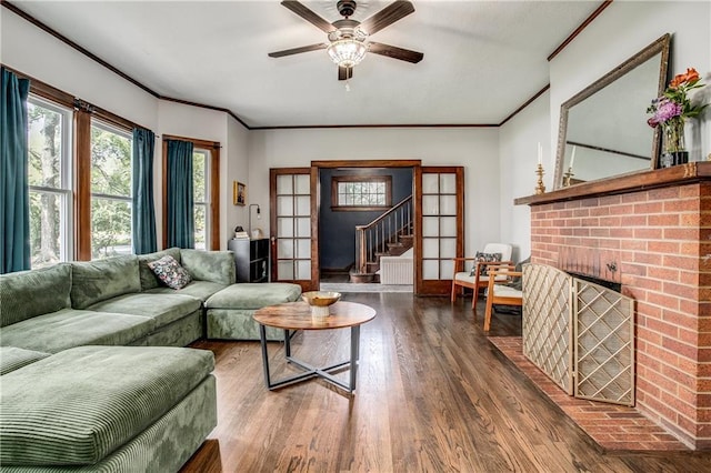 living room with a fireplace, hardwood / wood-style flooring, ceiling fan, crown molding, and french doors