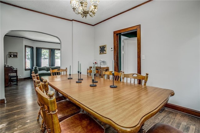 dining space with an inviting chandelier, dark wood-type flooring, and ornamental molding