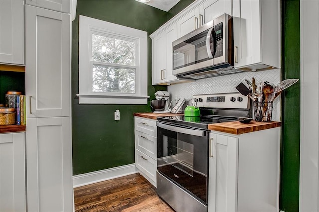 kitchen with butcher block counters, white cabinetry, appliances with stainless steel finishes, dark hardwood / wood-style floors, and decorative backsplash