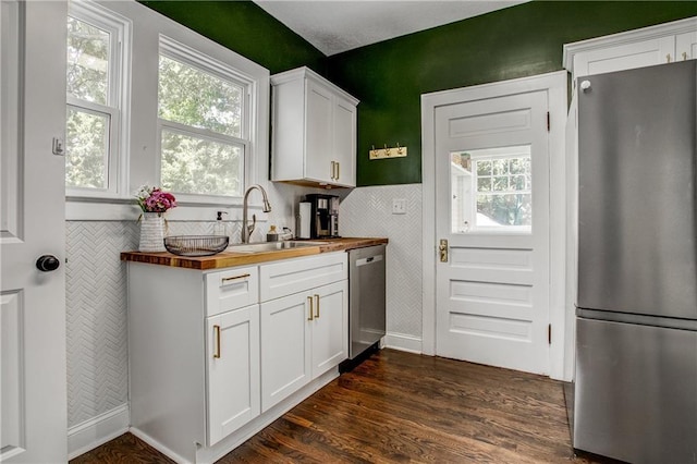 kitchen with stainless steel appliances, white cabinetry, sink, and wood counters