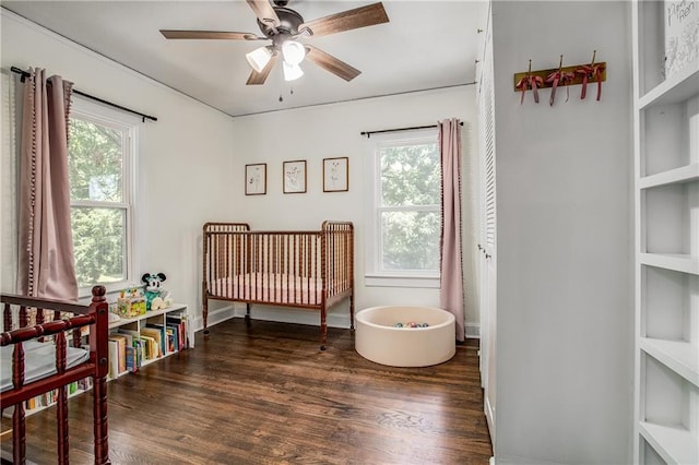 bedroom featuring dark wood-type flooring, multiple windows, and a crib