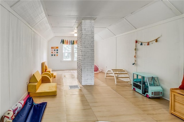 playroom featuring decorative columns, lofted ceiling, and hardwood / wood-style floors