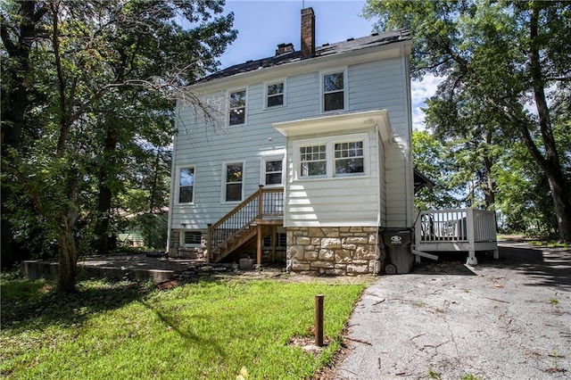 back of property featuring a wooden deck and a yard