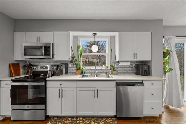 kitchen featuring white cabinetry, appliances with stainless steel finishes, sink, and pendant lighting